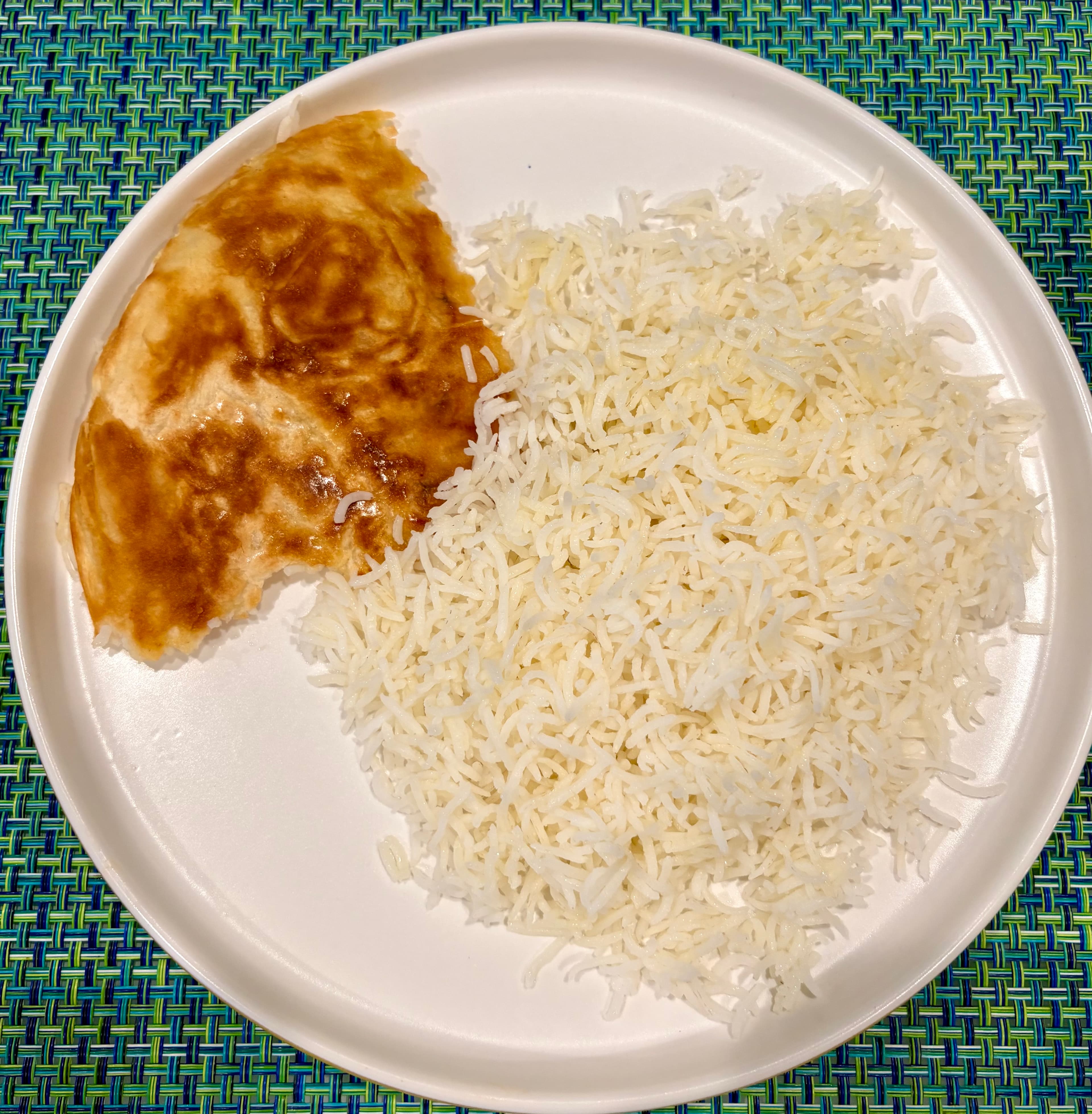 A plate of plain steamed basmati rice served with a piece of golden lavash tahdeeg