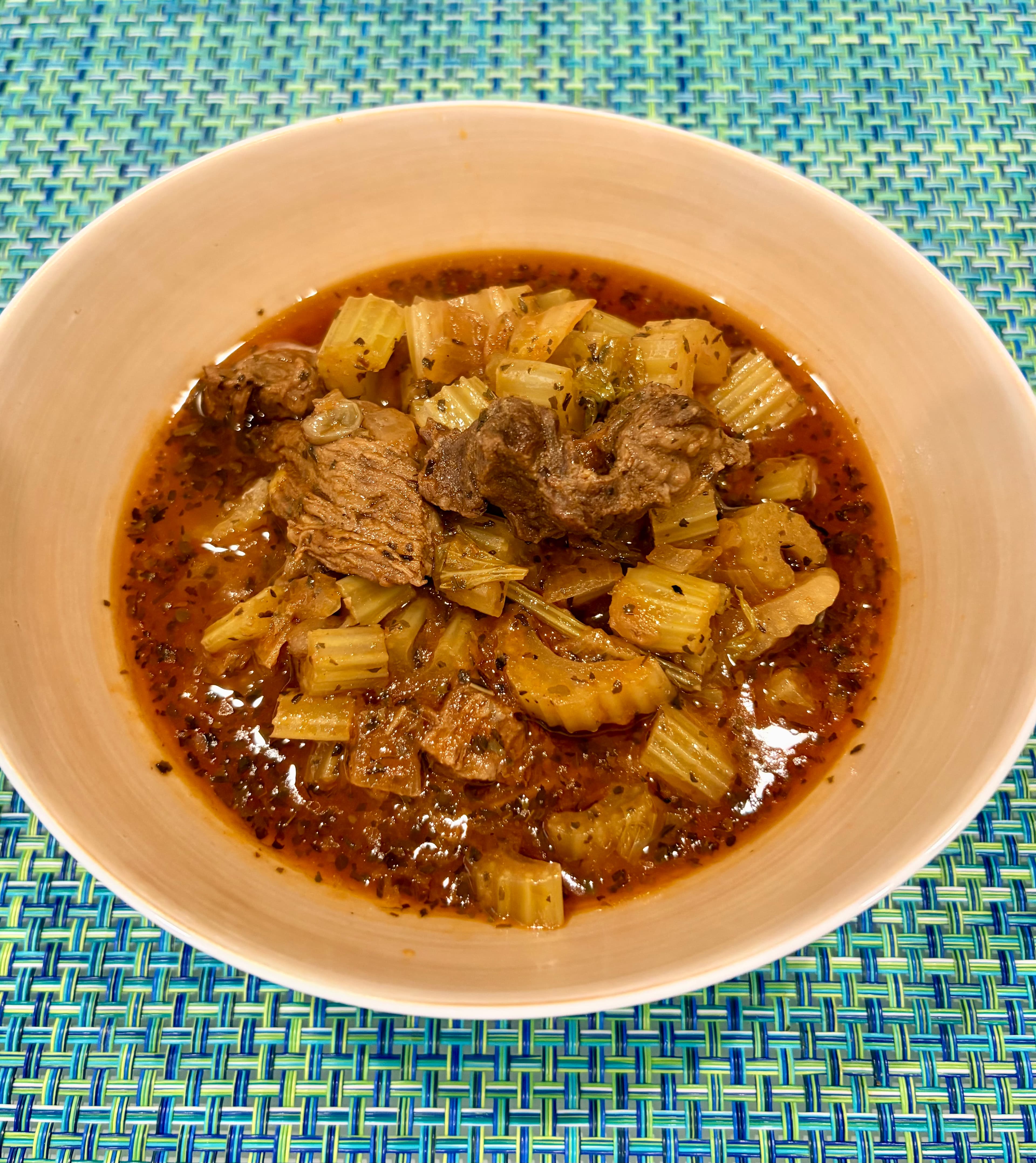 A bowl of celery stew with tender beef chunks, celery, and herbs in a rich brown sauce